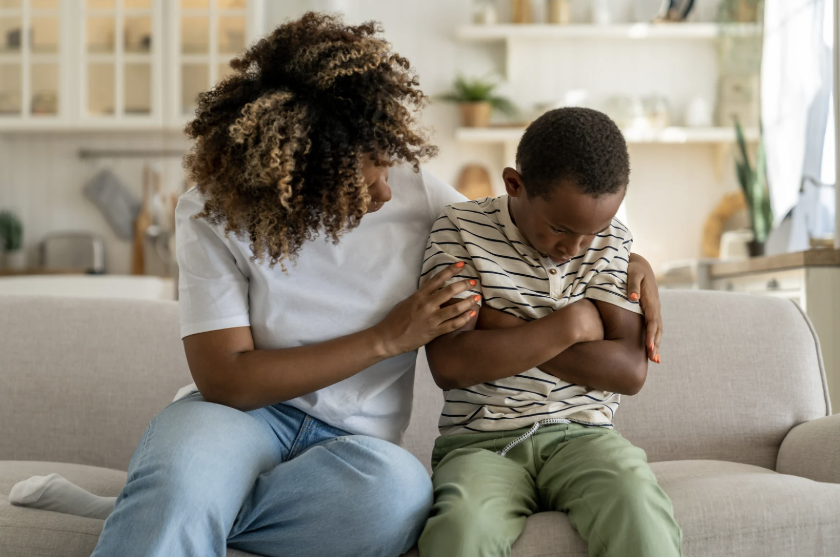 mother holding son with crossed arms